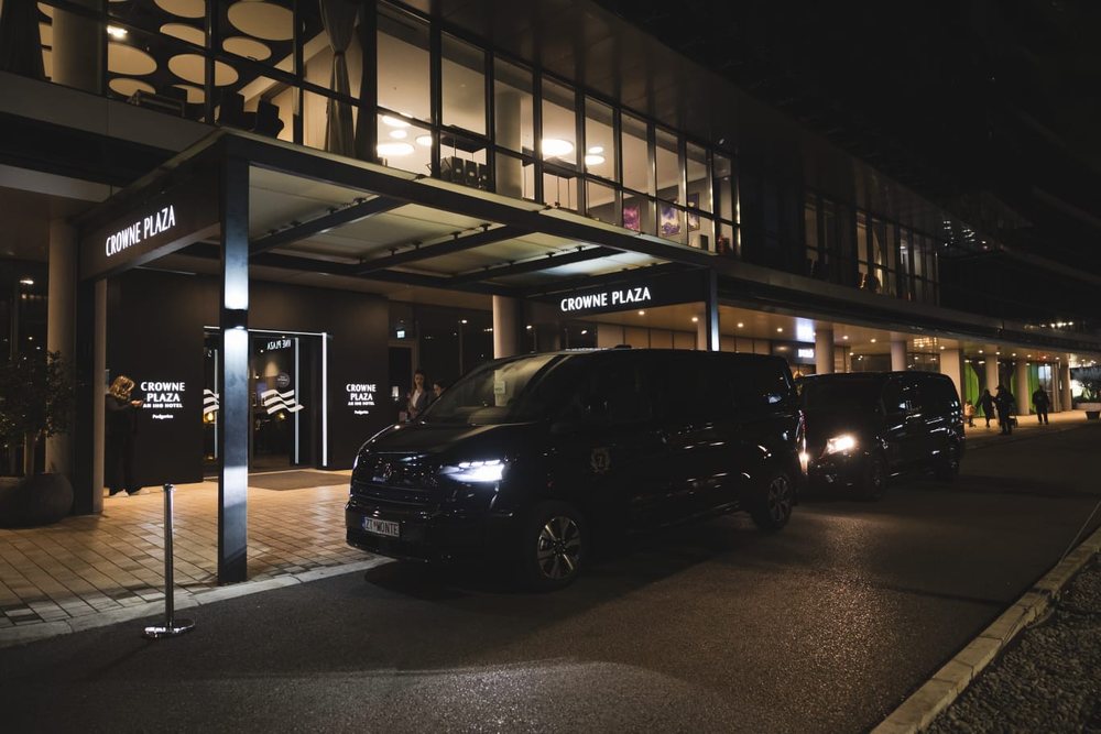 A Monte Zeta van waiting at the lit entrance of the Crowne Plaza hotel in Podgorica at night