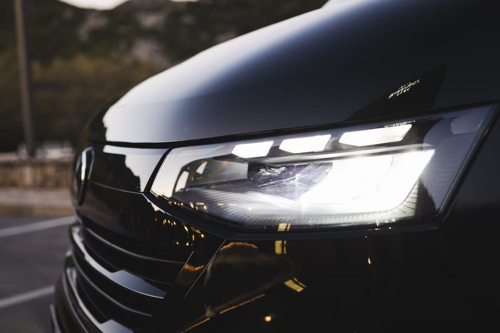 Close-up of the LED headlight of a black Volkswagen van at dusk