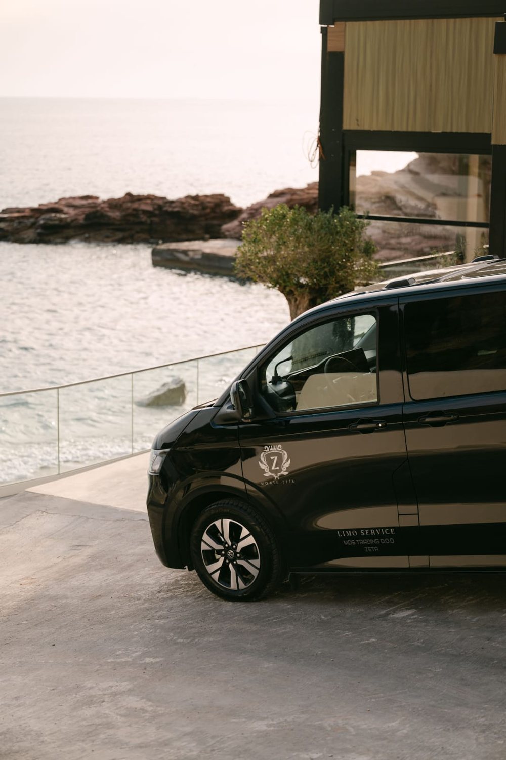 Monte Zeta crest on the front door of a black Volkswagen Caravelle above the sea